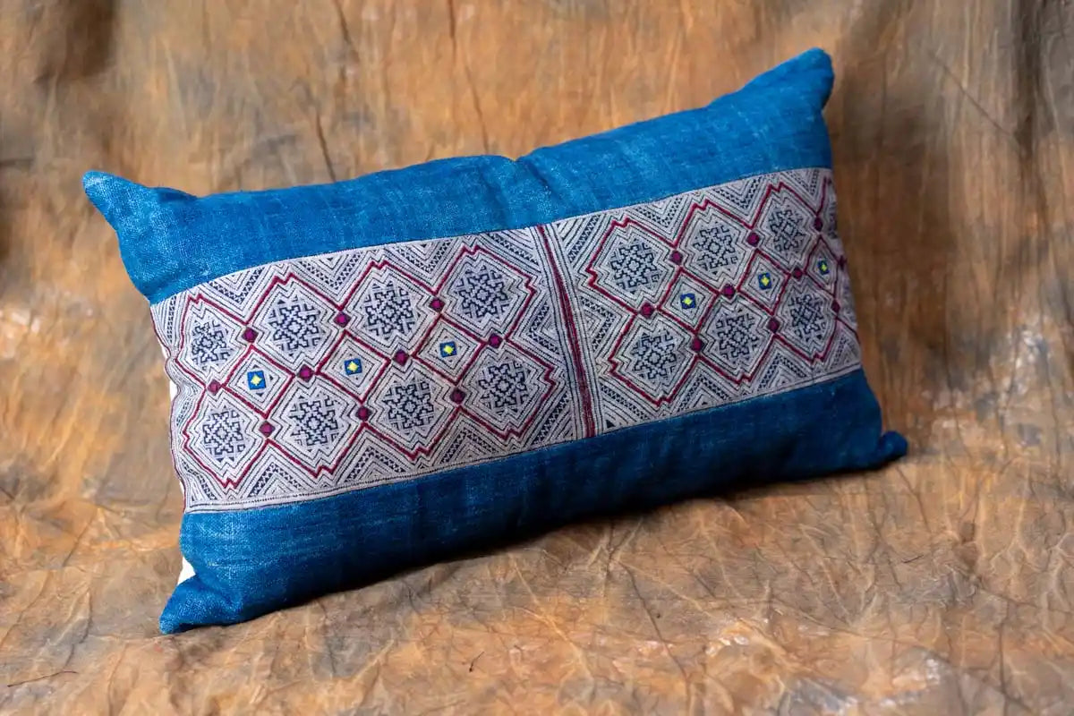 Indigo batik cushion on rustic wooden surface in natural light