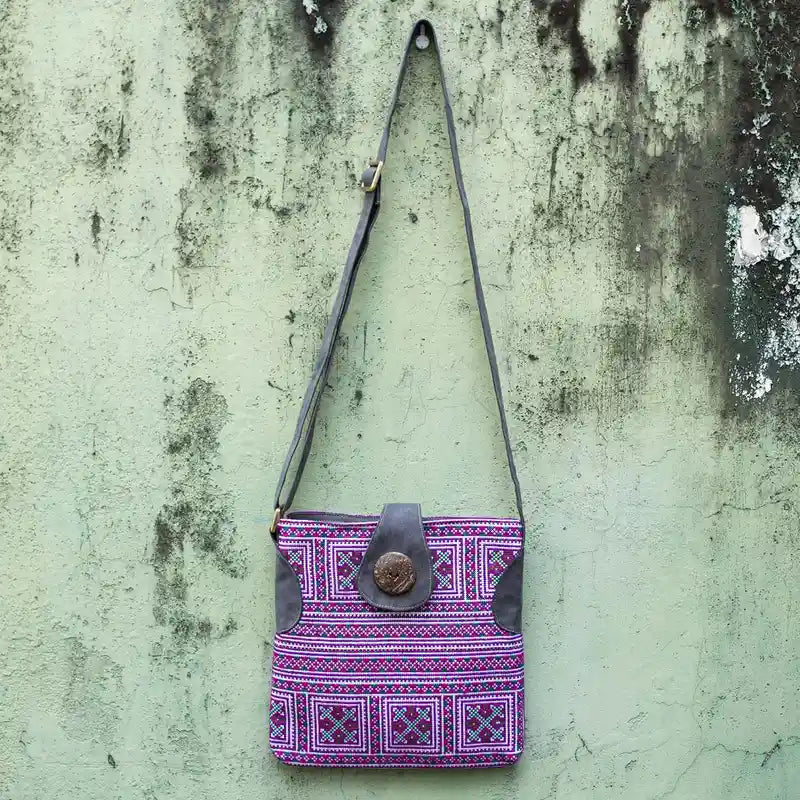 Vindigo purple embroidered crossbody bag hanging front view against rustic wall background