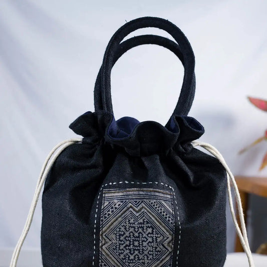 Close-up of black hemp bucket bag with vintage H’Mong patch and drawstring closure