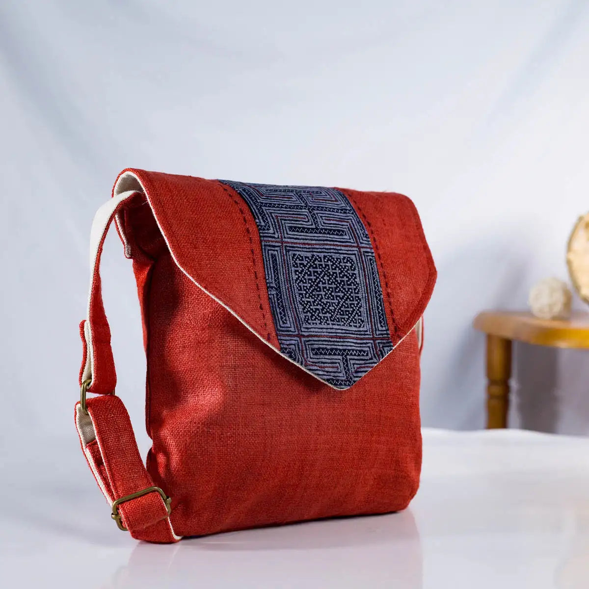 Angled view of red hemp cross-body bag with vintage H’Mong fabric patch, sustainable artisanal bag
