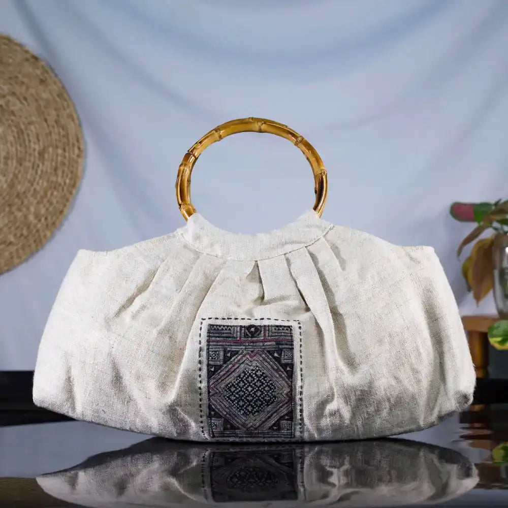 Front view of hemp handbag with bamboo handle and H’mong patch, artisan-crafted sustainable fashion.