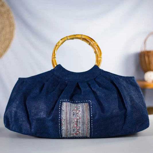Front display of indigo hemp handbag with bamboo handles and H’mong patch, eco-friendly.