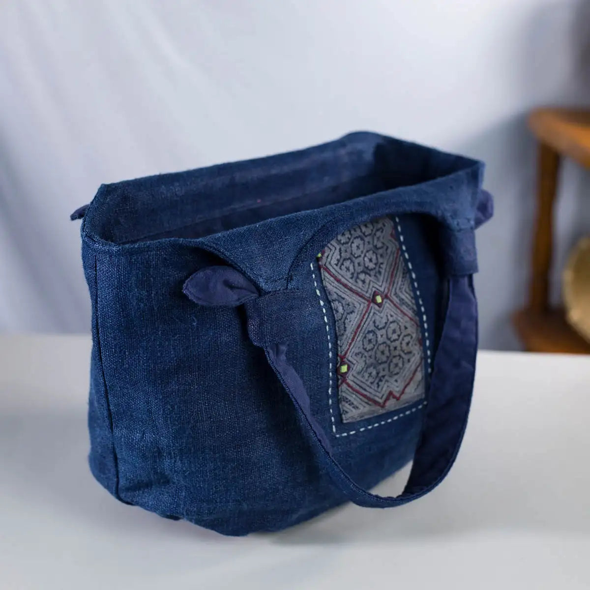 Side view of indigo hemp tote bag with spacious design and H’mong patch detail, artisan-crafted.