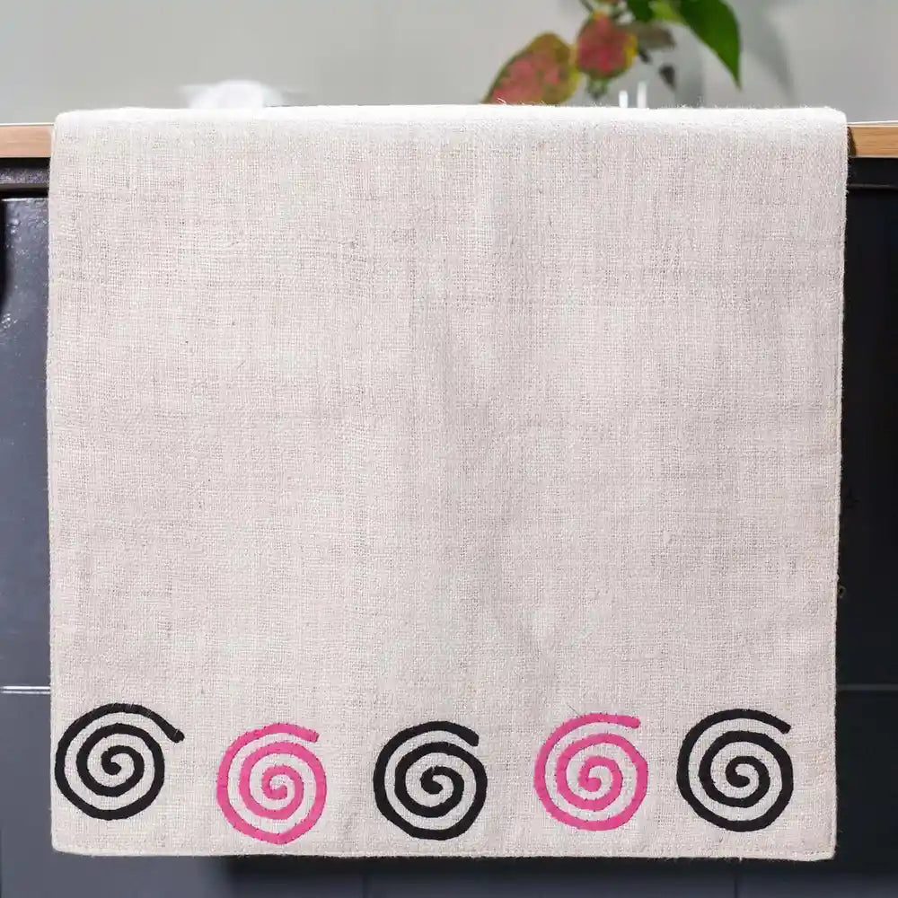 Vindigo beige hemp table runner end view decorated with pink and black spiral stitching