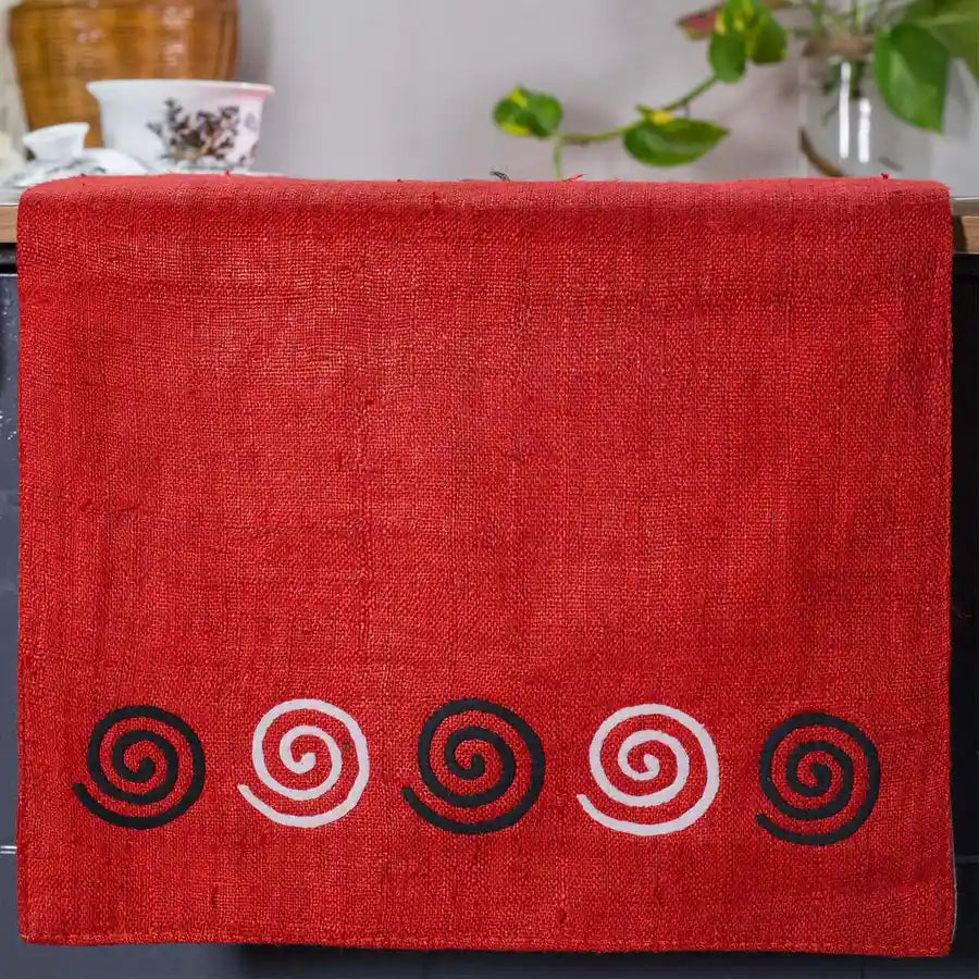 Vindigo red hemp table runner end view showing alternating black and white spiral motifs