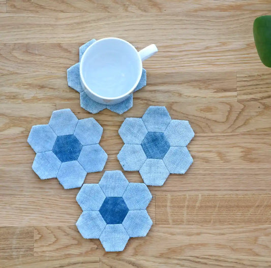 Set of blue denim hexagon flower coasters arranged on wooden table