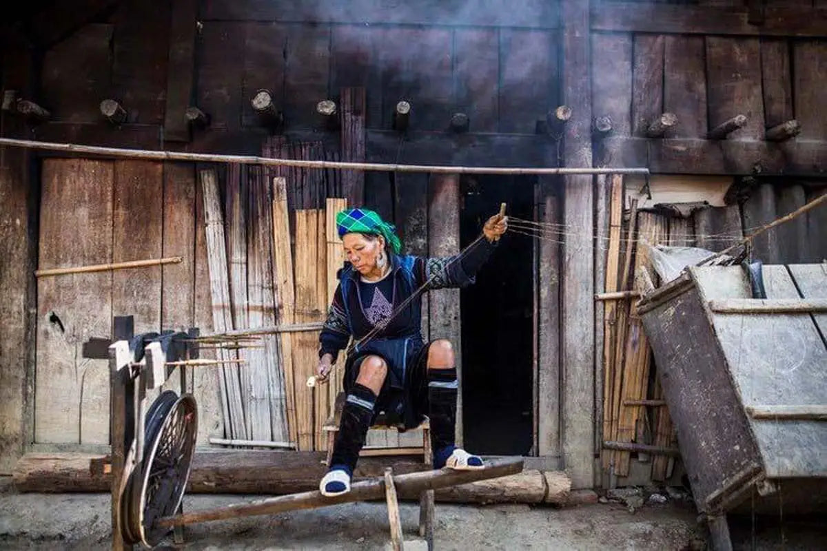 Vindigo artisan posing with deep green hemp fabric roll outdoors