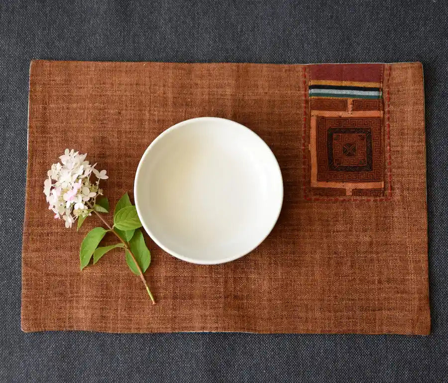 Brunt linneunderlägg med tribalruta och skål i naturlig dukning