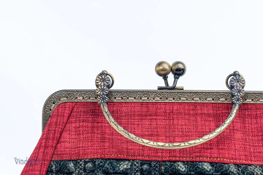 Vindigo close-up of copper handle and kiss-lock clasp on red handbag
