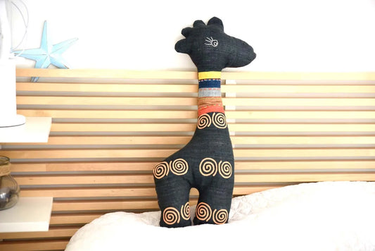 Blue spiral handmade deer toy posed upright on wooden headboard