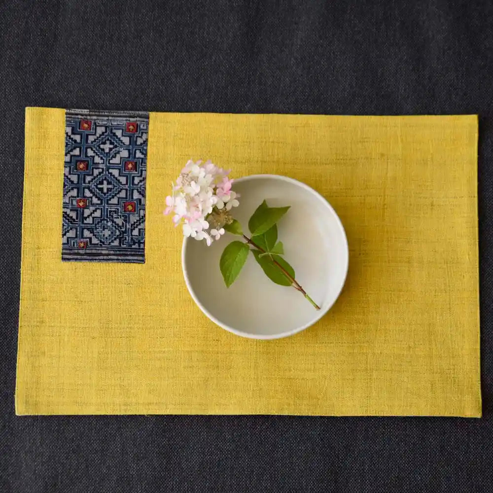 Flatlay of yellow hemp placemat and indigo-patterned napkin