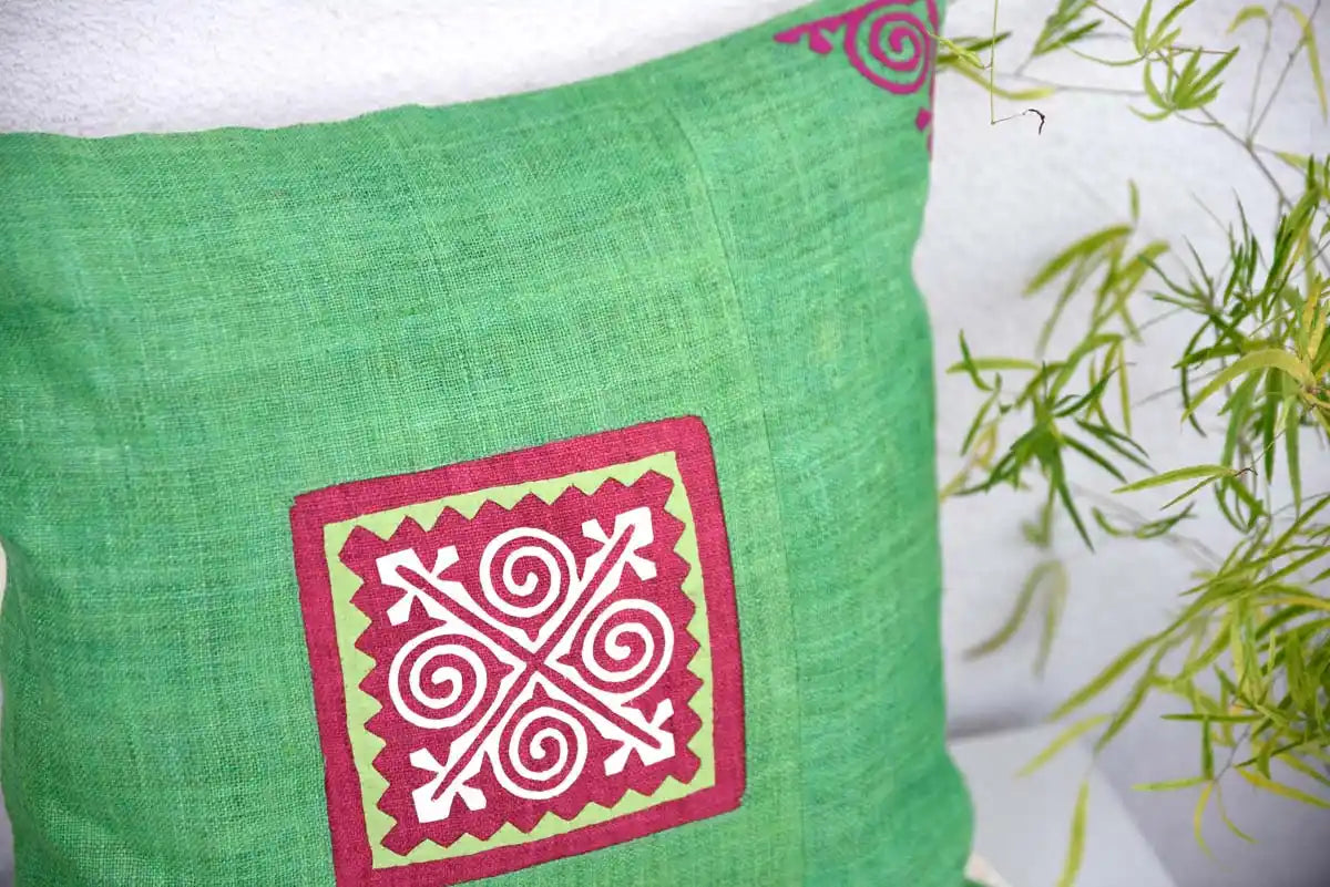 Close-up of hand-stitched red spiral patch on green hemp cushion