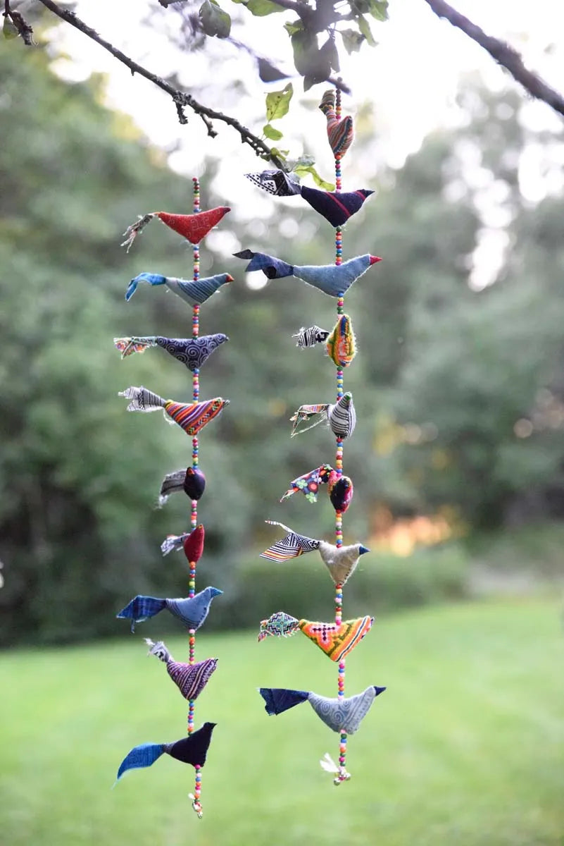 Hängande blå och vita tygfåglar i en gren utomhus