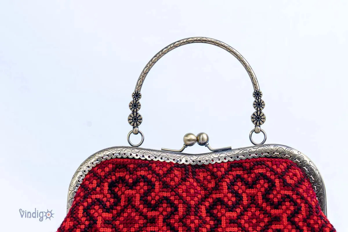 Vindigo close-up of carved copper handle on red embroidered handbag