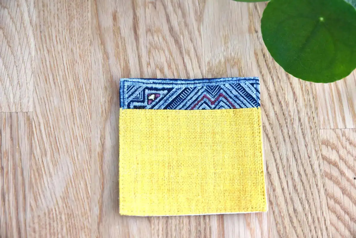 Top view of handmade yellow hemp coaster with indigo detail