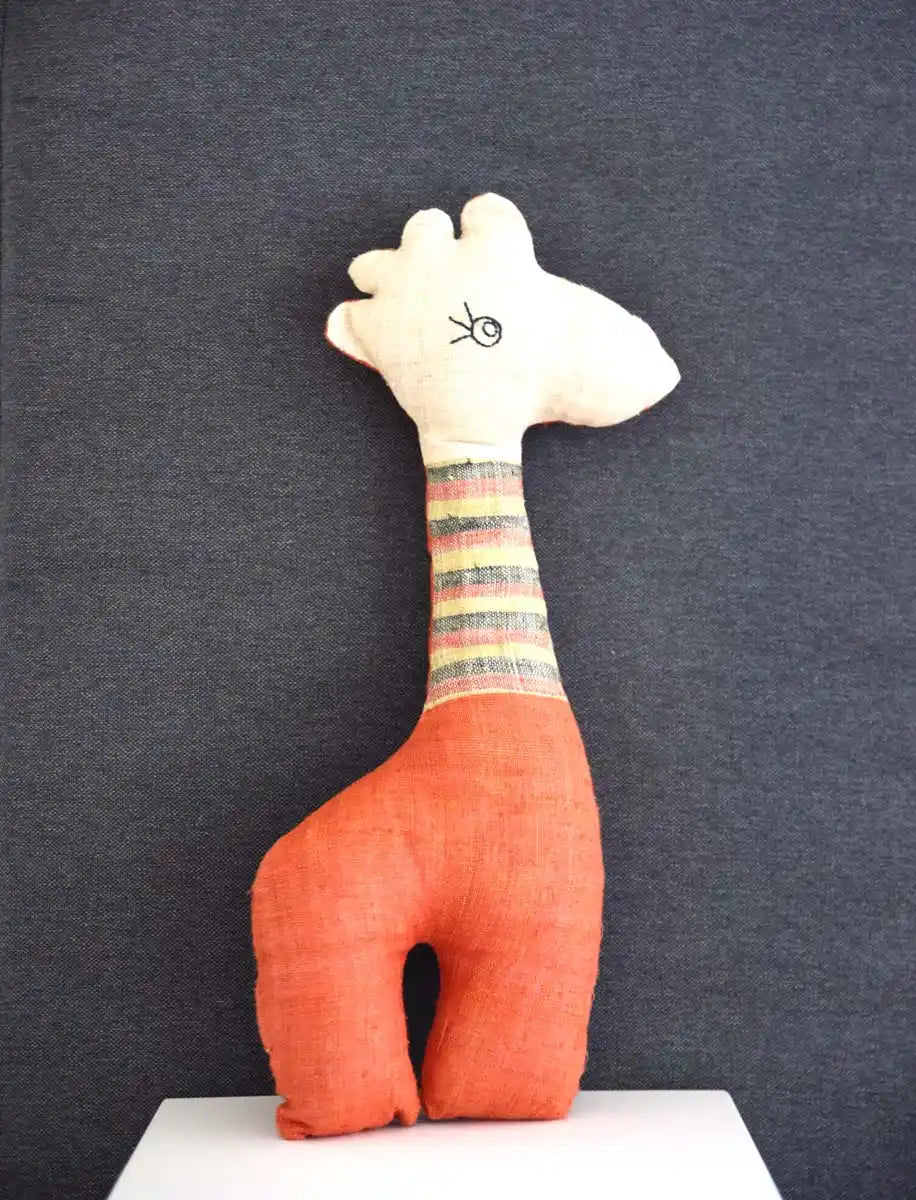 Orange stuffed deer toy with striped neck on grey background