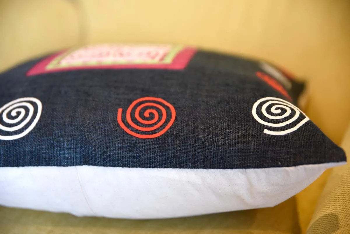 Side view of black cushion with pink spiral embroidery