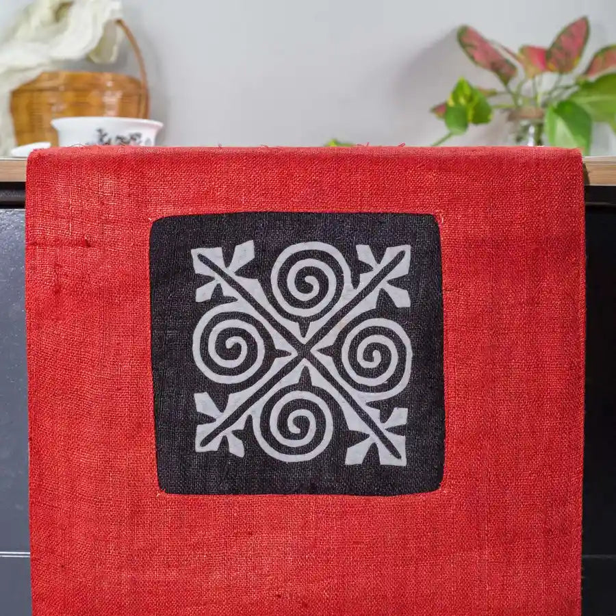 Vindigo red hemp table runner close-up showing intricate white and black spiral embroidery