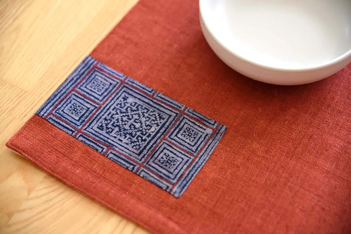 Flatlay of burgundy hemp placemat showing indigo woven accent