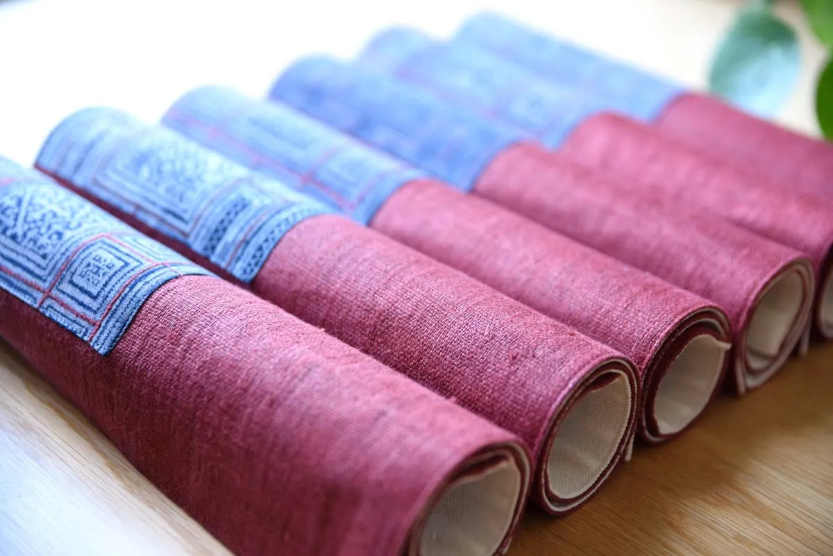 Mixed rolls of indigo and burgundy hemp napkins neatly arranged