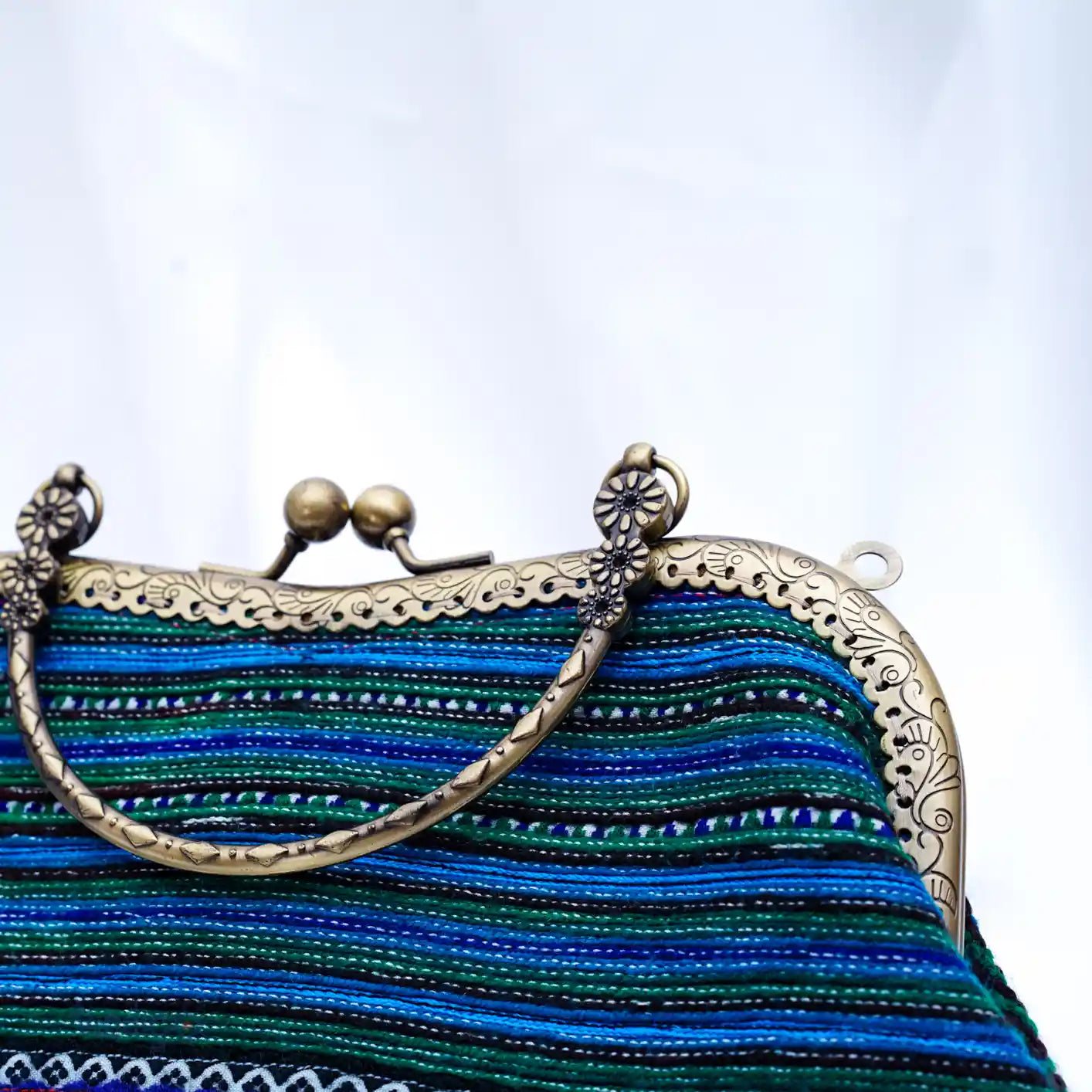 Detalj av metallhandtag och stängning på blå väska i tribaltyg