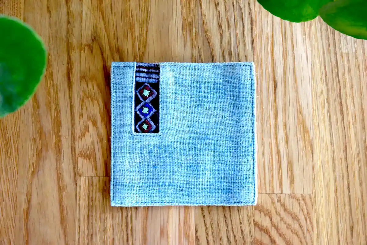 Geometric tribal embroidery on light denim coaster surface
