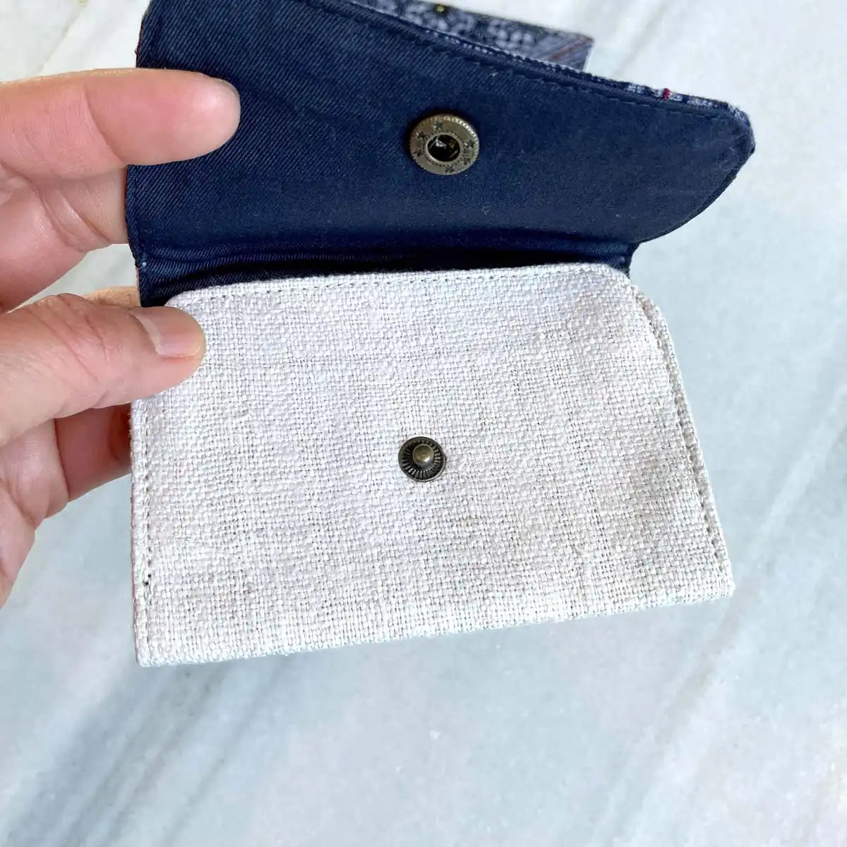 Vindigo cardholder shown open with navy flap and white pocket