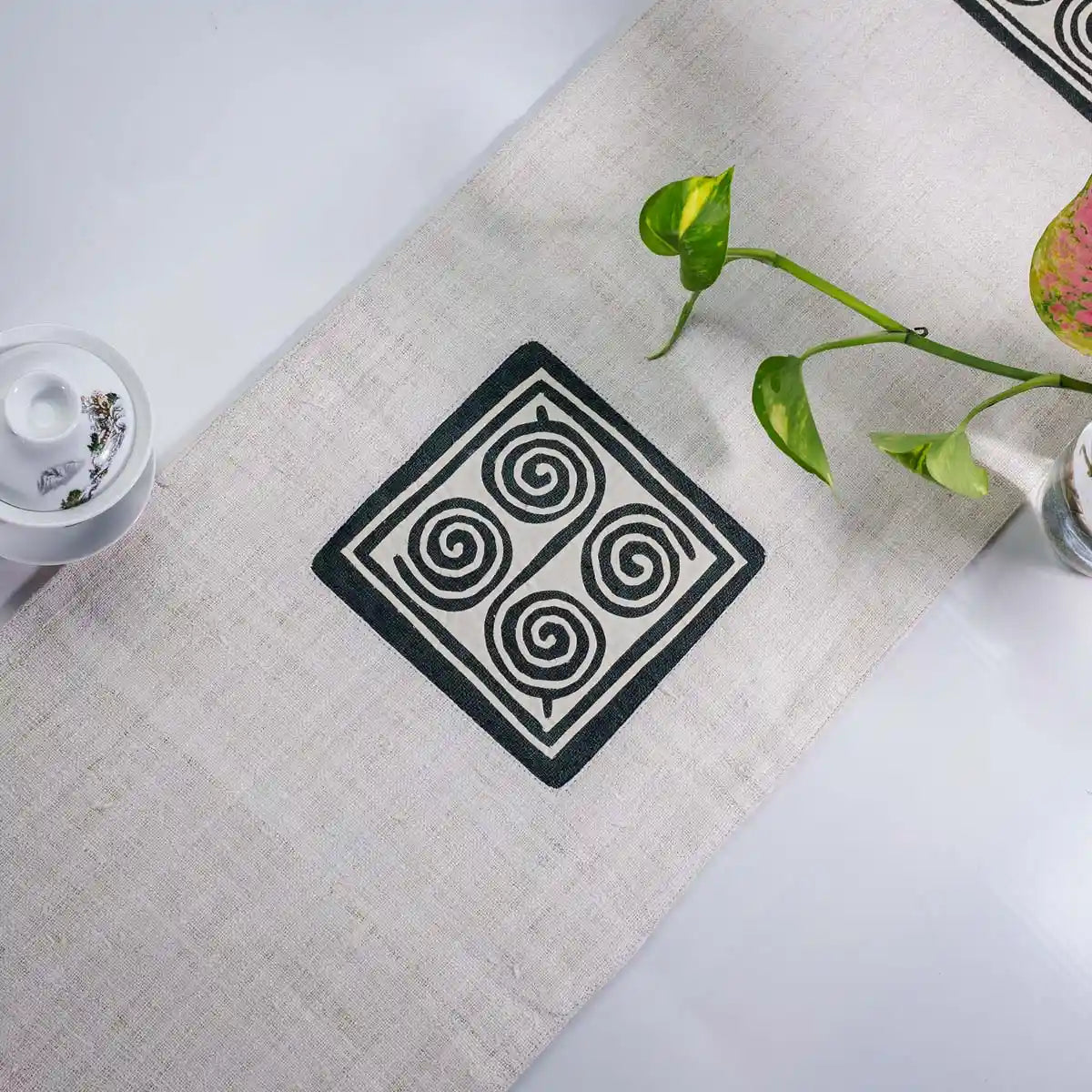 Vindigo beige hemp table runner angled view displaying geometric embroidery pattern