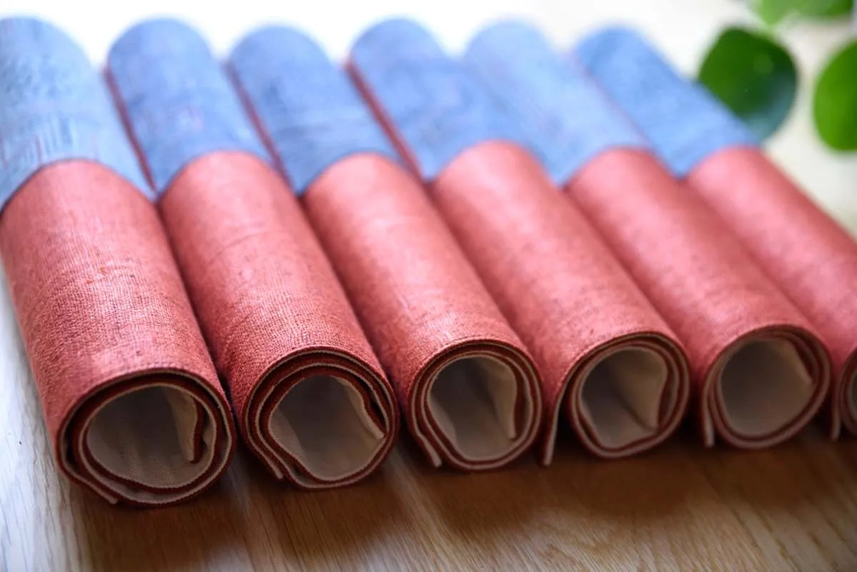 Neatly arranged rolls of hemp napkins in burgundy and indigo tones