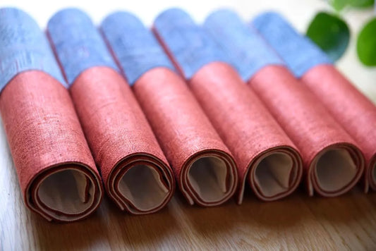 Neatly arranged rolls of hemp napkins in burgundy and indigo tones