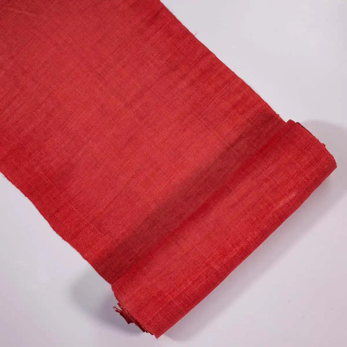Vindigo red hemp fabric roll partially unrolled on white background
