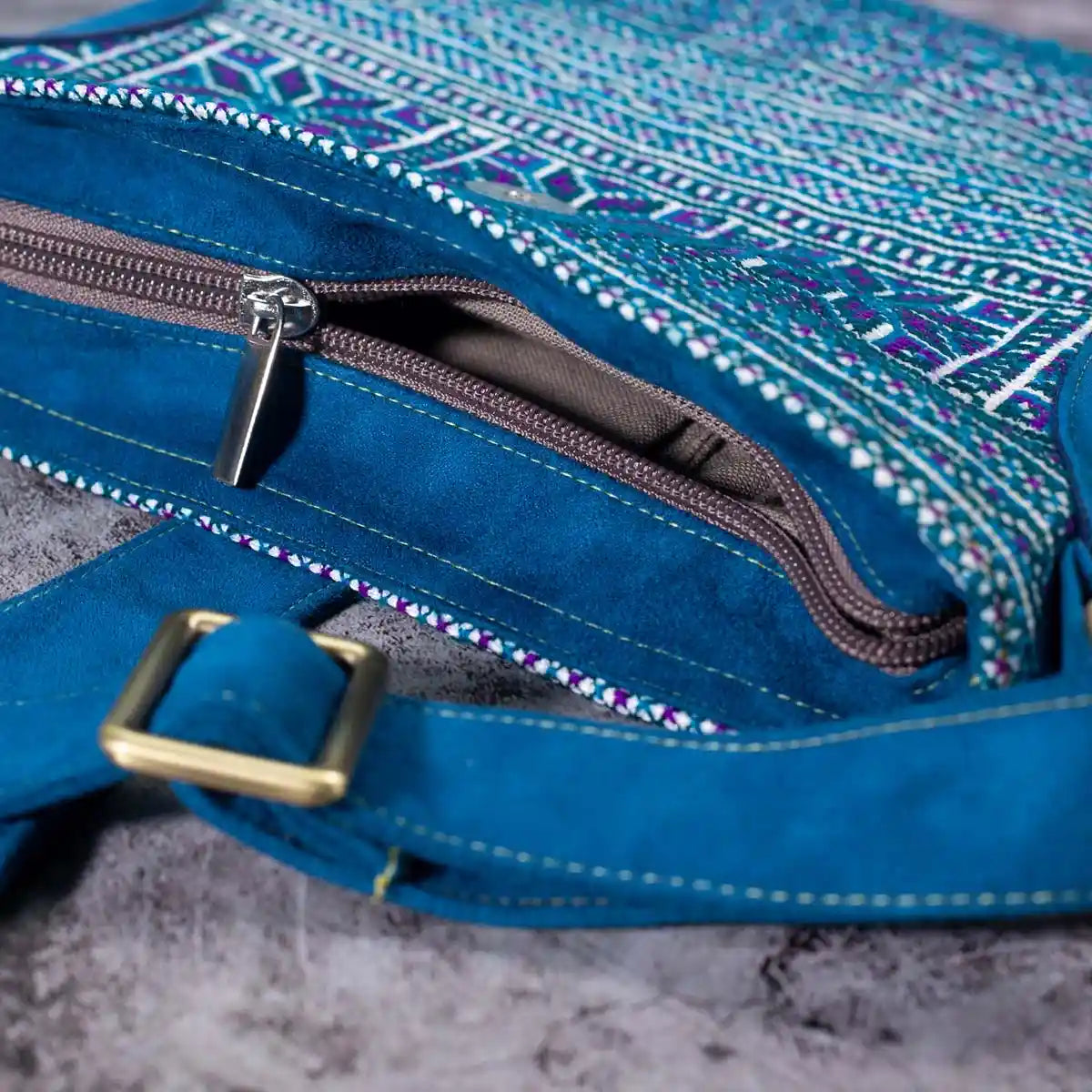 Vindigo blue embroidered crossbody bag zipper and strap close-up with metal buckle