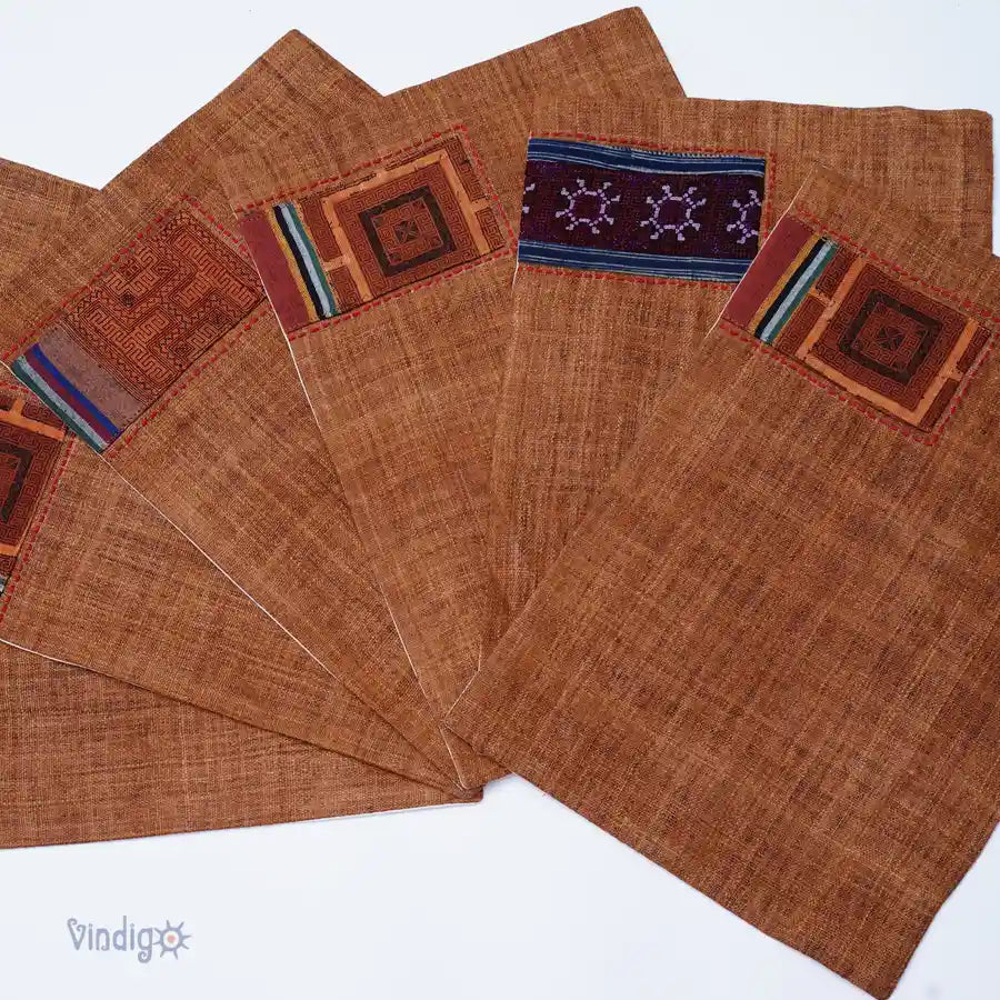 Uppställning av flera bruna tygunderlägg med varierande tribalbroderier