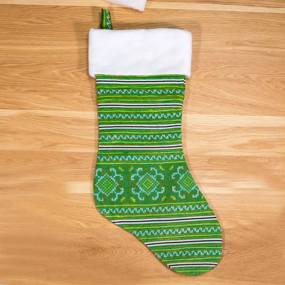 Vindigo green geometric embroidered Christmas stocking with white cuff on wooden surface