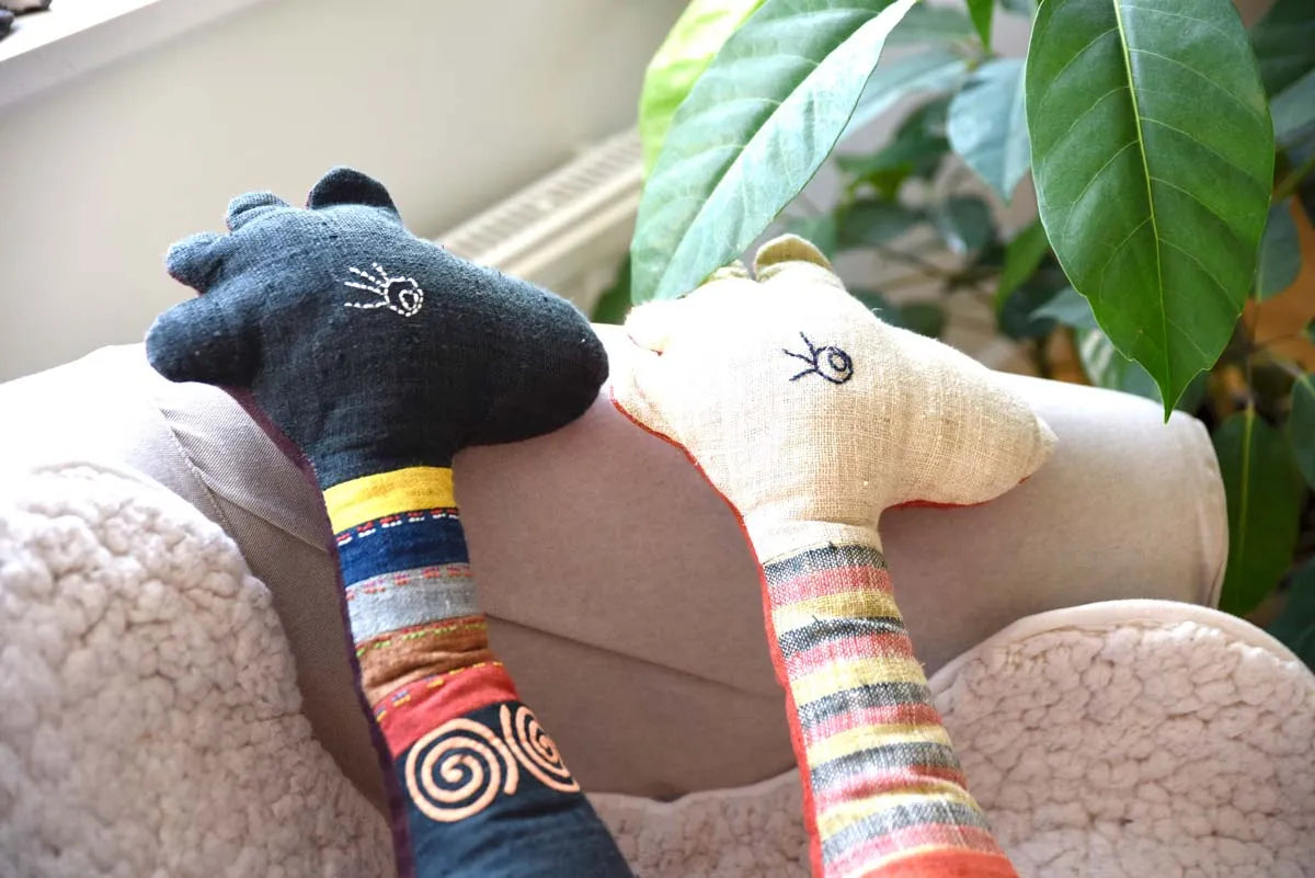 Close-up of two deer faces, one dark blue, one beige with lashes