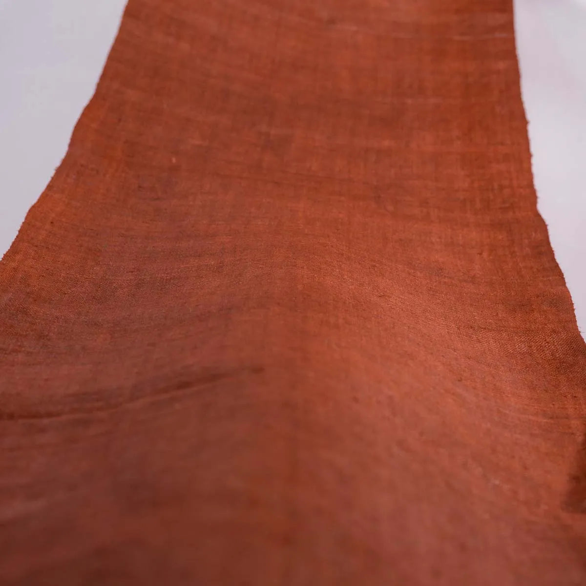 Vindigo orange hemp fabric roll extended on white surface