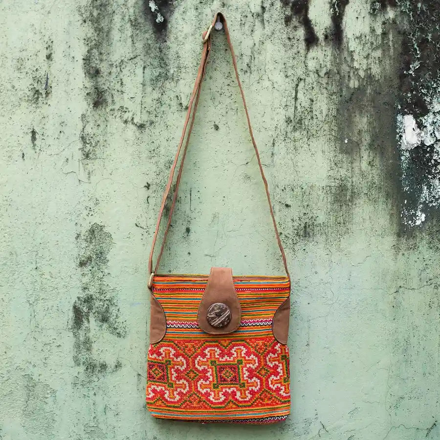 Vindigo orange hemp crossbody bag hanging front view against textured wall background