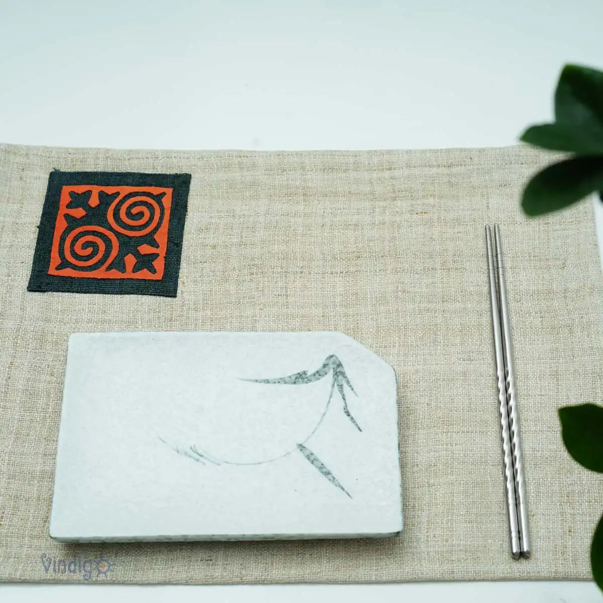 Blå tygservett med orange tribalruta dukad på bord i ljus miljö