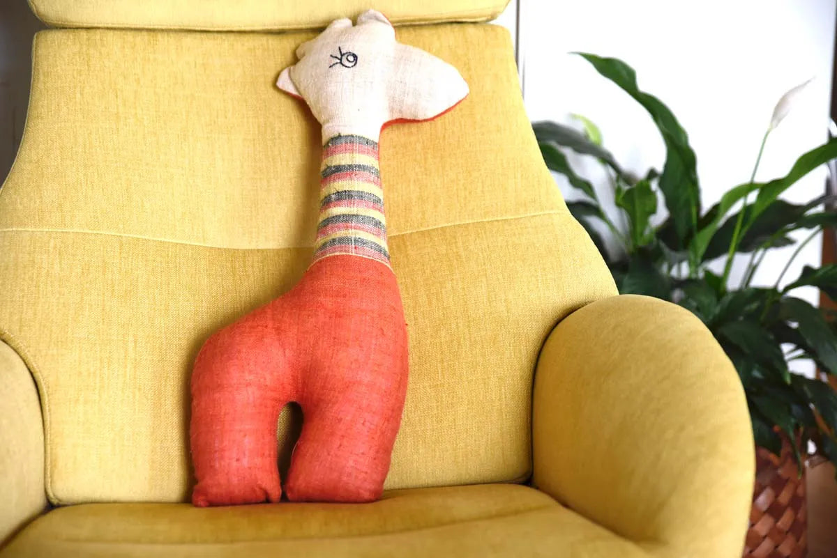 Orange Vindigo stuffed deer toy on yellow armchair