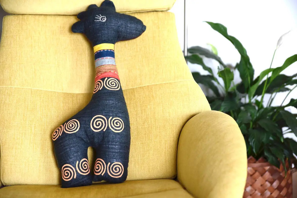 Side view of spiral embroidered deer plushie sitting on bed