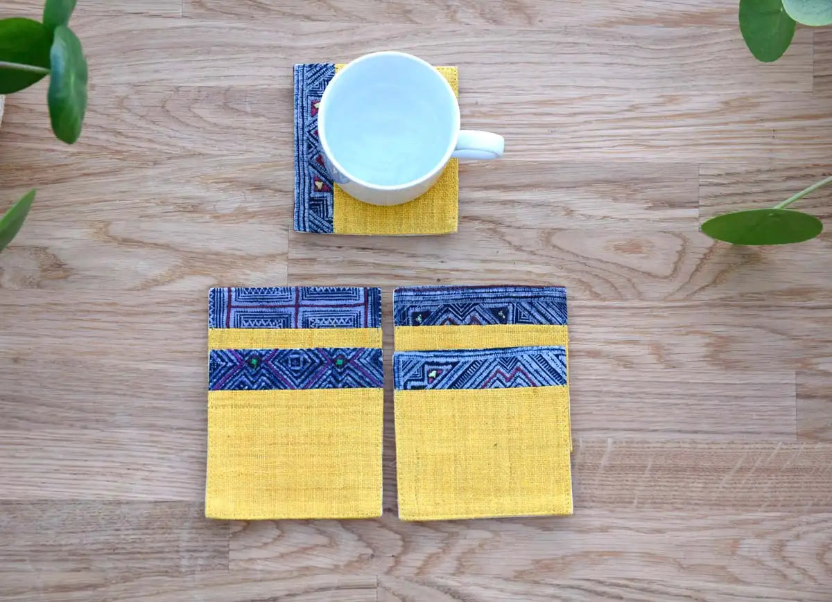 Set of four yellow hemp coasters arranged neatly on table