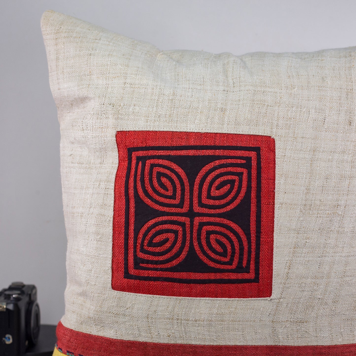 Beige hampa kudde med ränder i olika färger, handsytt mönster i svart och röd