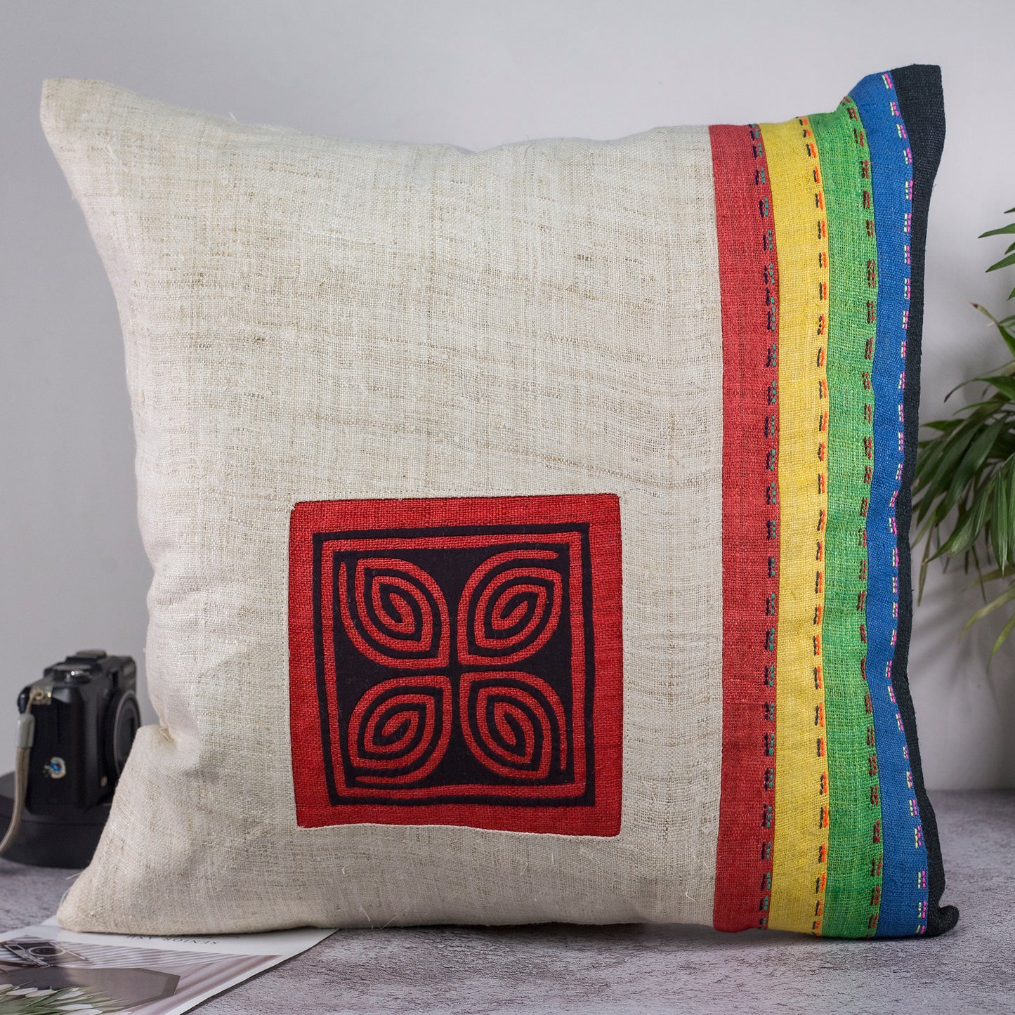 Beige hampa kudde med ränder i olika färger, handsytt mönster i svart och röd