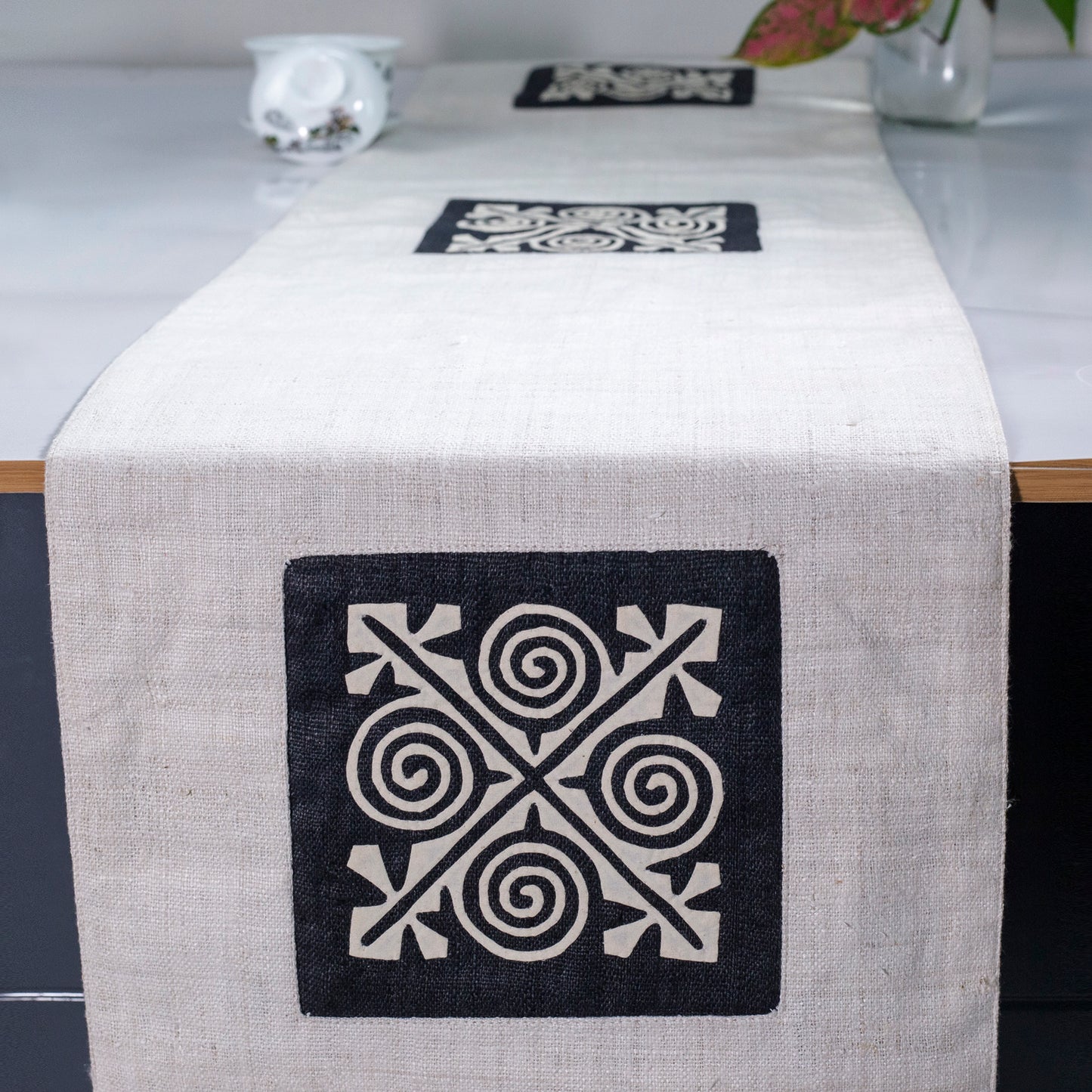 White Hemp Table Runner, white patch on black background, spiral patches in pink and black at two ends