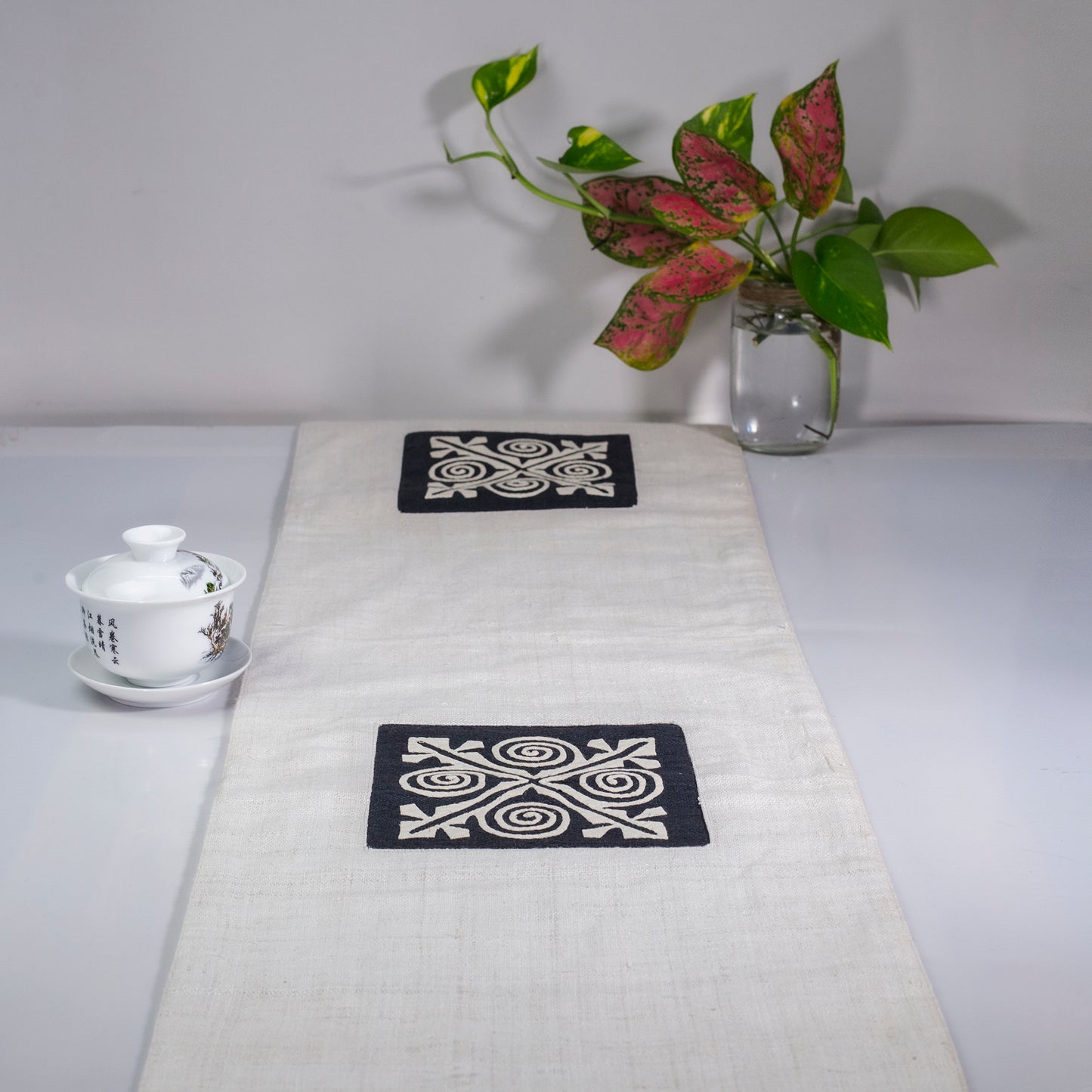 White Hemp Table Runner, white patch on black background, spiral patches in pink and black at two ends