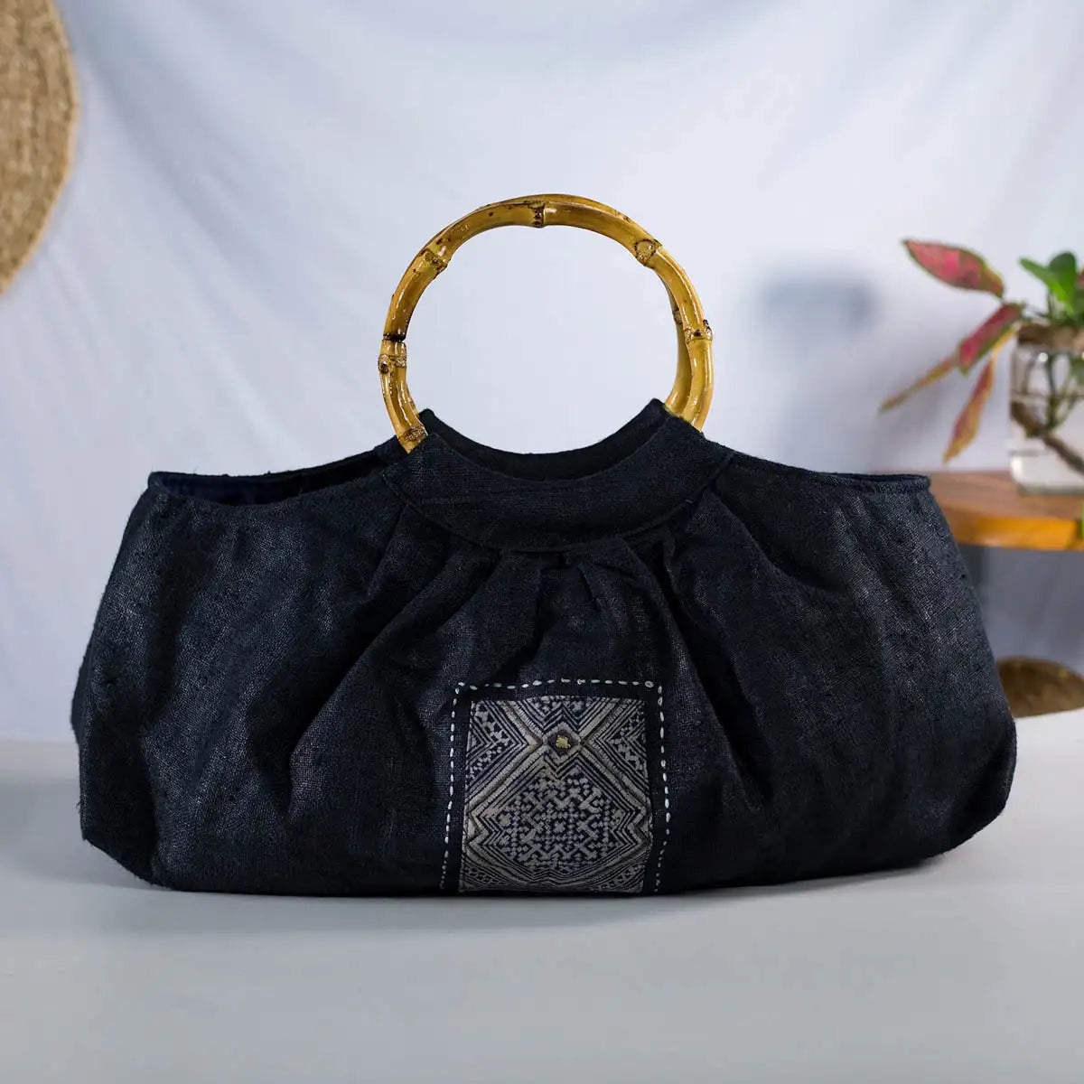 Front view of black hemp handbag with bamboo handle and H’Mong batik patch, eco-friendly bag.