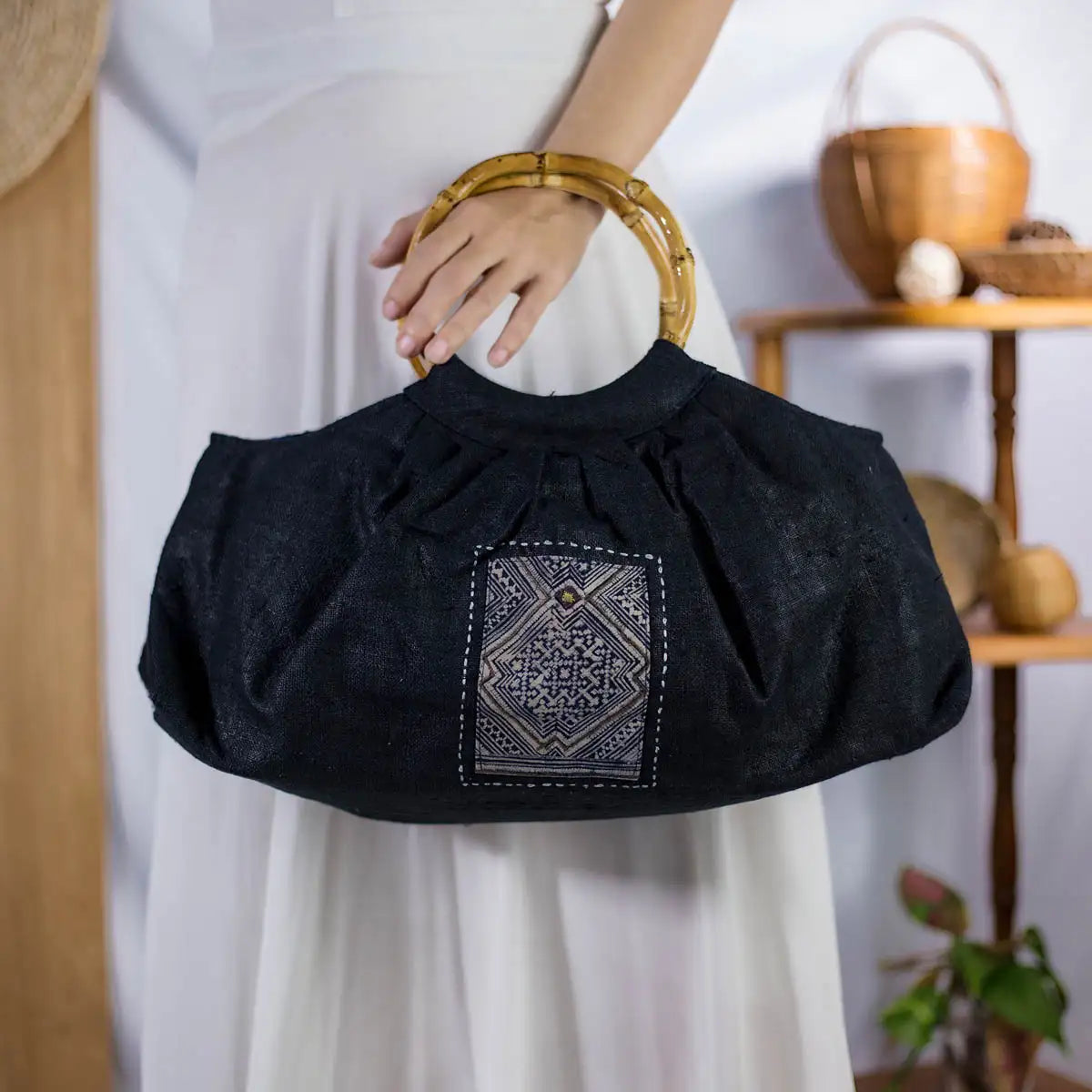 Model holding black hemp handbag with bamboo handle and H’Mong patch, sustainable fashion