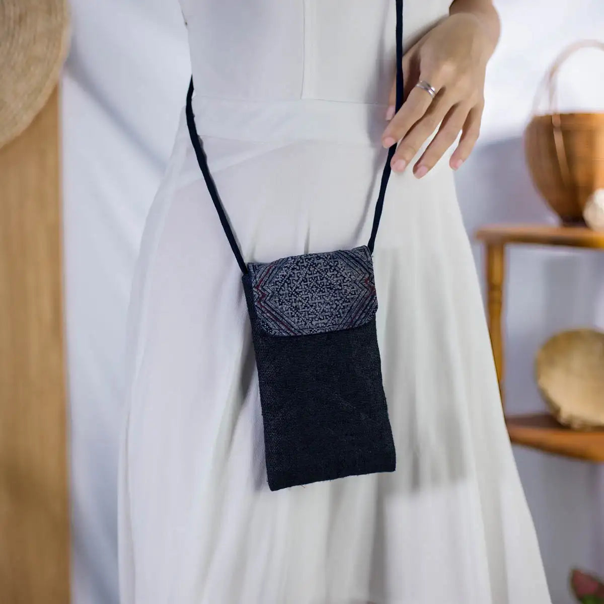 Model wearing black hemp phone bag with long strap and H’Mong patch, sustainable handmade accessory.
