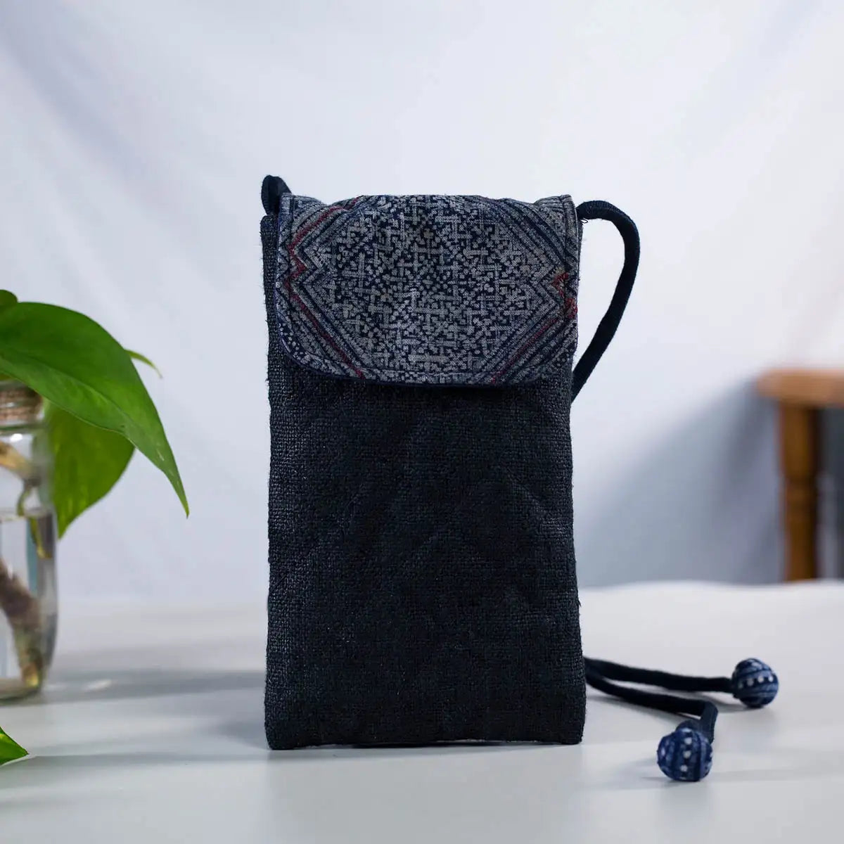 Upright view of black hemp phone bag with H’Mong patch and adjustable strap, eco-friendly Purity Collection.