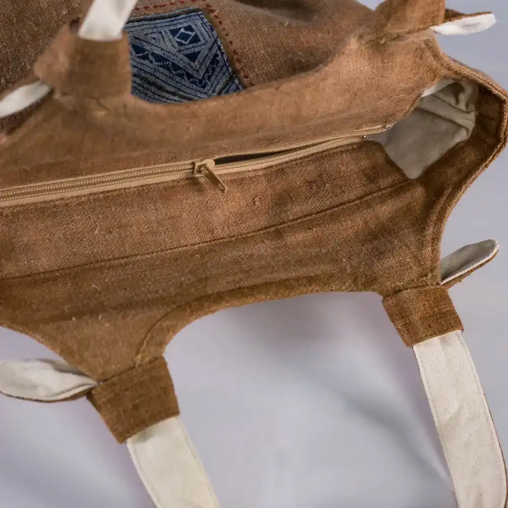 Close-up of brown hemp handbag showing tied fabric handles and lining detail, eco-friendly fashion.